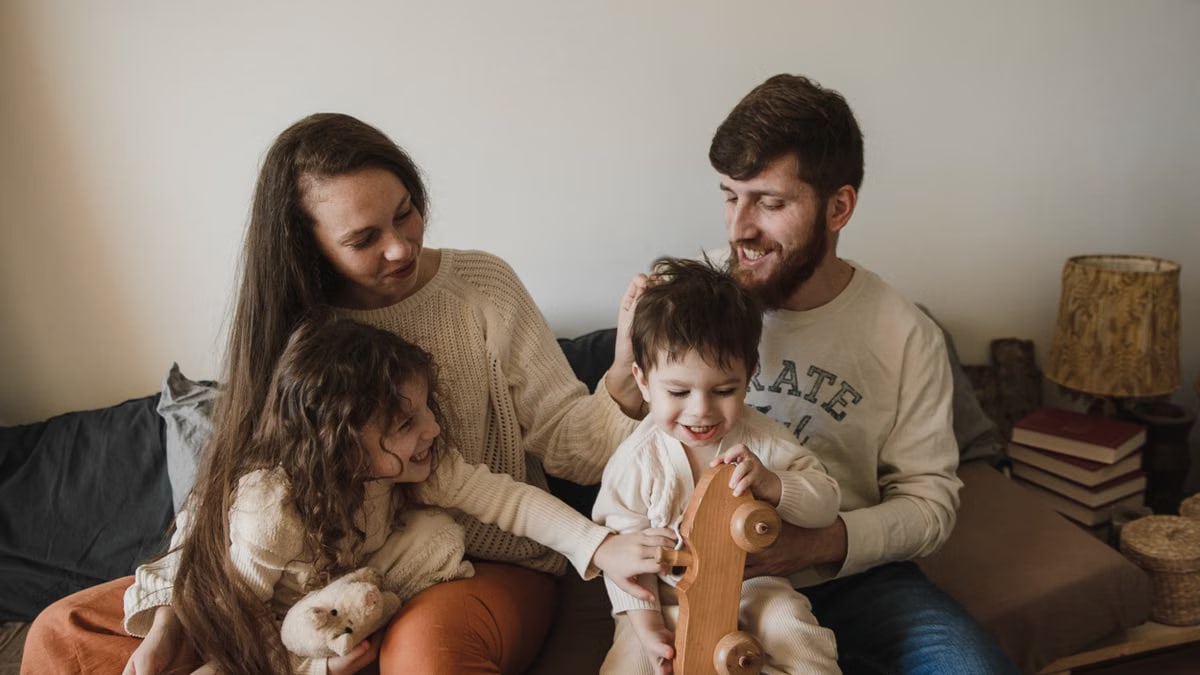 A joyful family of four sitting together on a sofa, enjoying their time with toys.